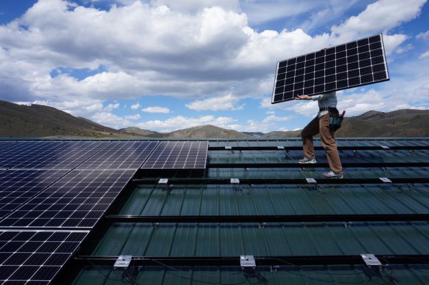 Person installing solar panel on roof