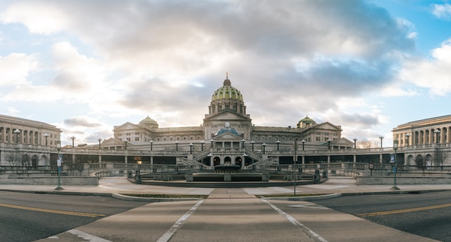 View of the Pennsylvania capital building in Harrisburg from across a street on a cloudy day.
