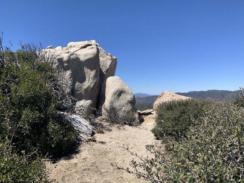 A rocky summit with distant mountains in view.