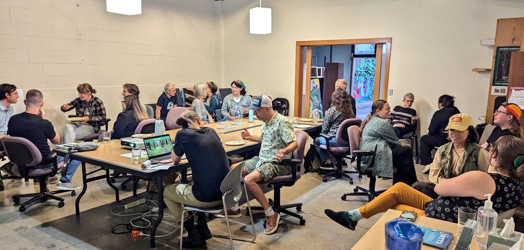 A group of people sit around a conference room table talking