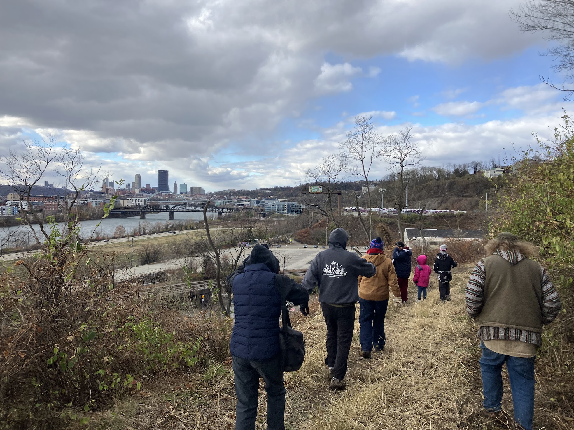 People walking on a grassy path with a view of Pittsburgh