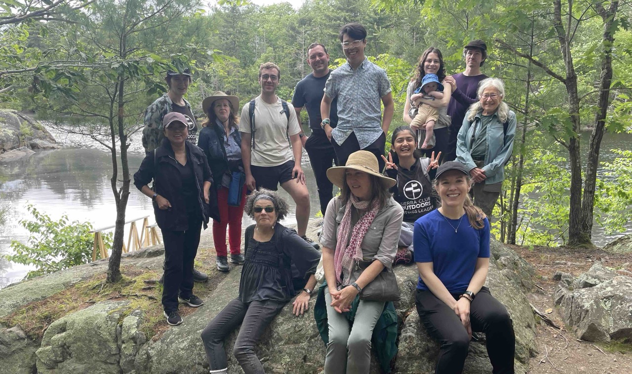 A group of people sitting in front of a pond in Wompatuck State Park