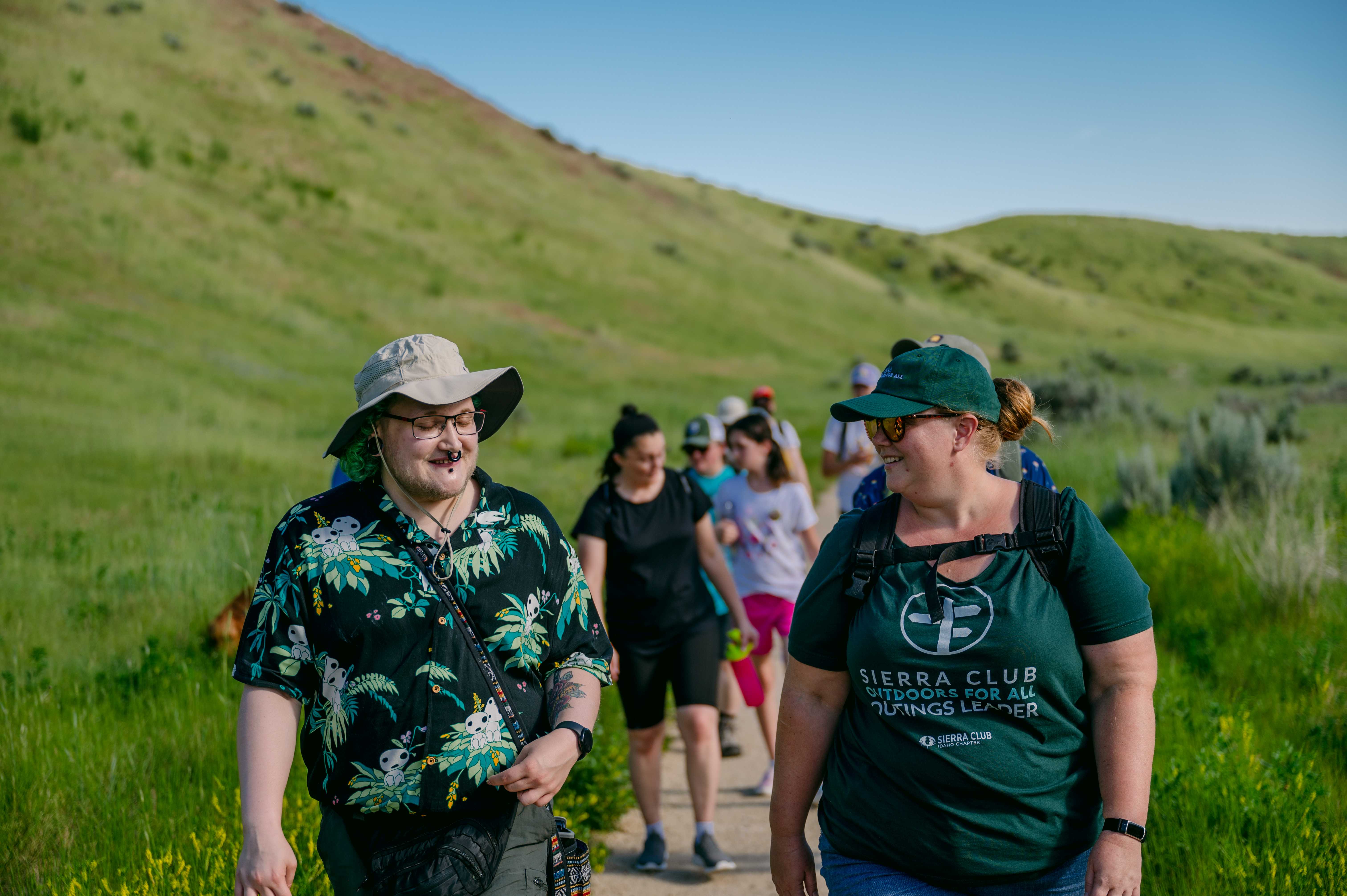 Idaho Sierra Club leader walks at the front of a group on a Foothills hike, making conversation with a participant