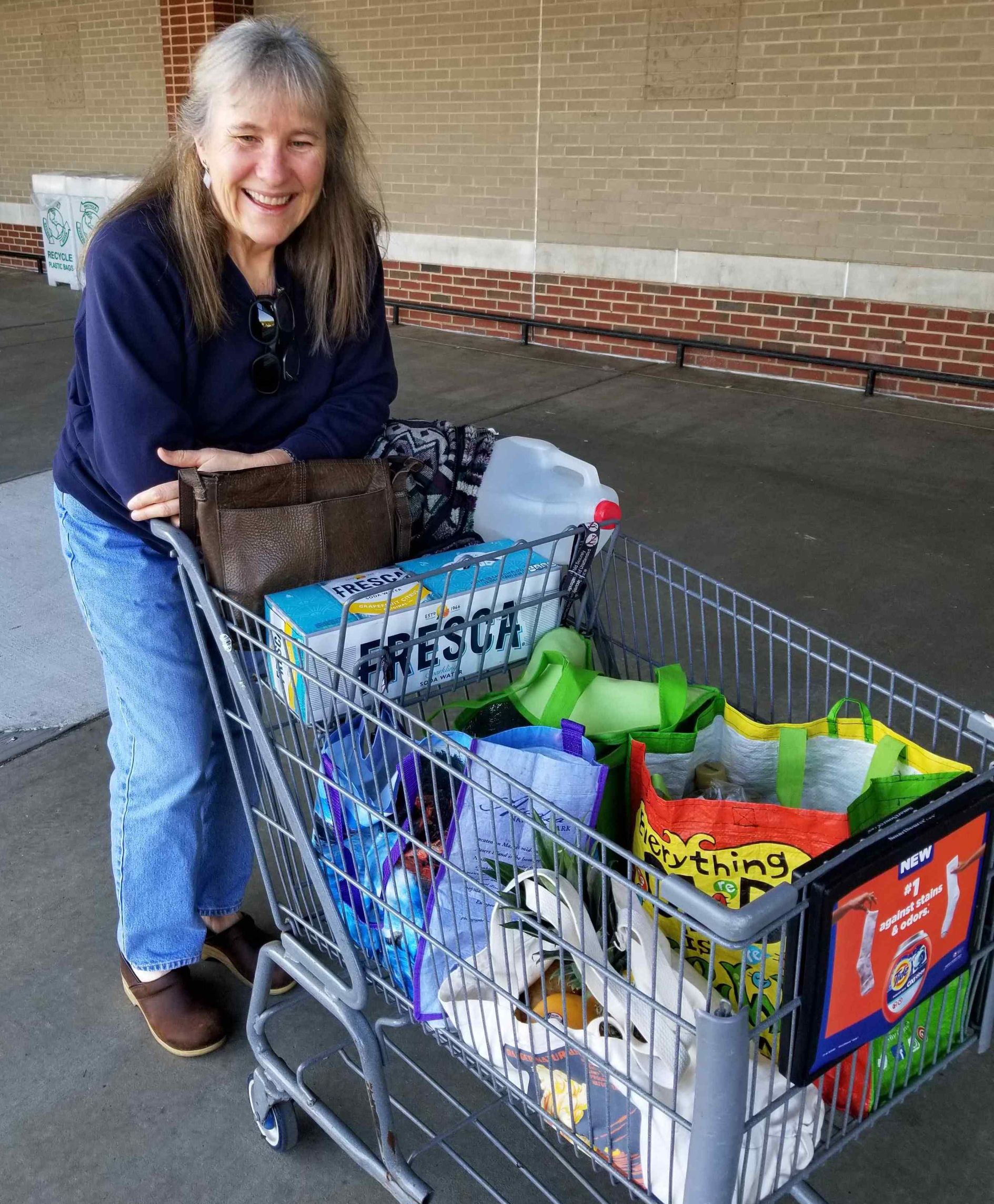 Shopper with cart full of reusable bags
