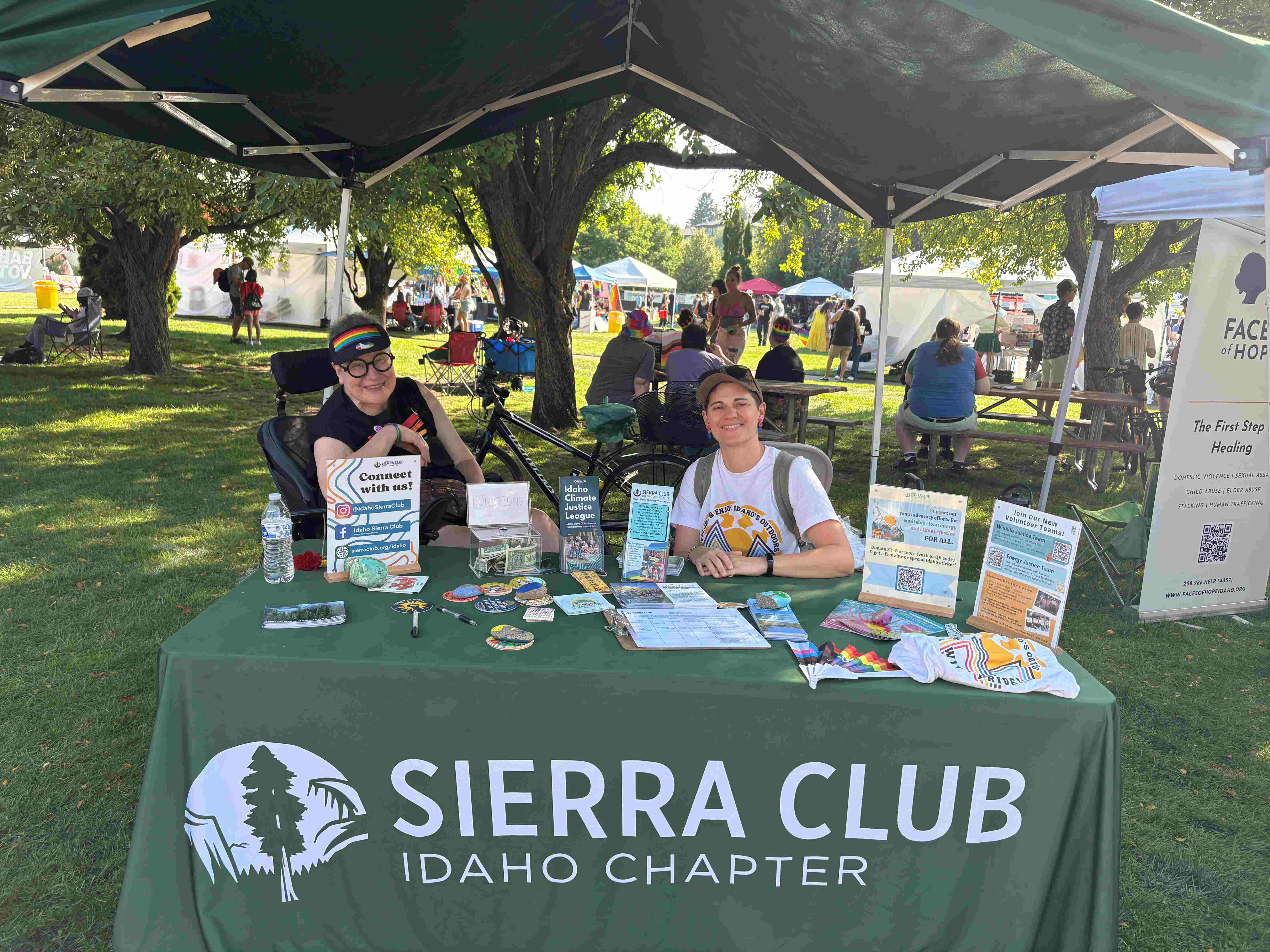Two volunteers sit smiling at an Idaho Sierra Club booth at the Boise Pride Festival
